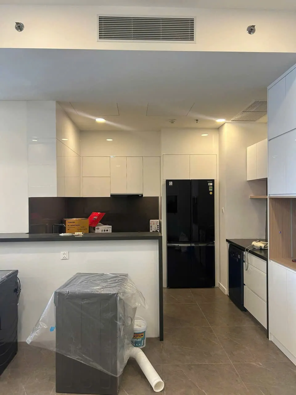 Tổng thể bếp căn hộ Berkley với đảo bếp mặt đá đen và hệ tủ kịch trần trắng