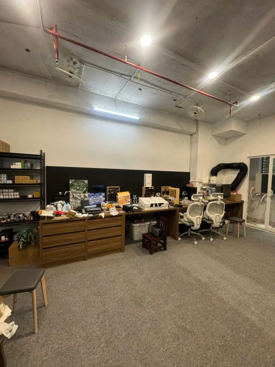 Khu văn phòng phía sau shop mô hình với tủ hồ sơ gỗ và kệ khung sắt