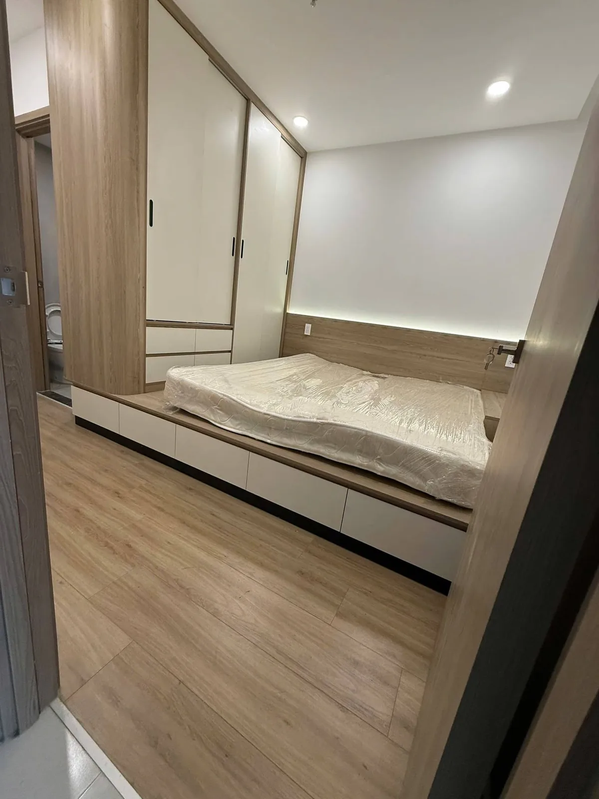 Phòng ngủ giường bục hộc kéo Phòng ngủ căn hộ Eastmark City với giường bục có hộc kéo và tủ áo cánh lùa trắng