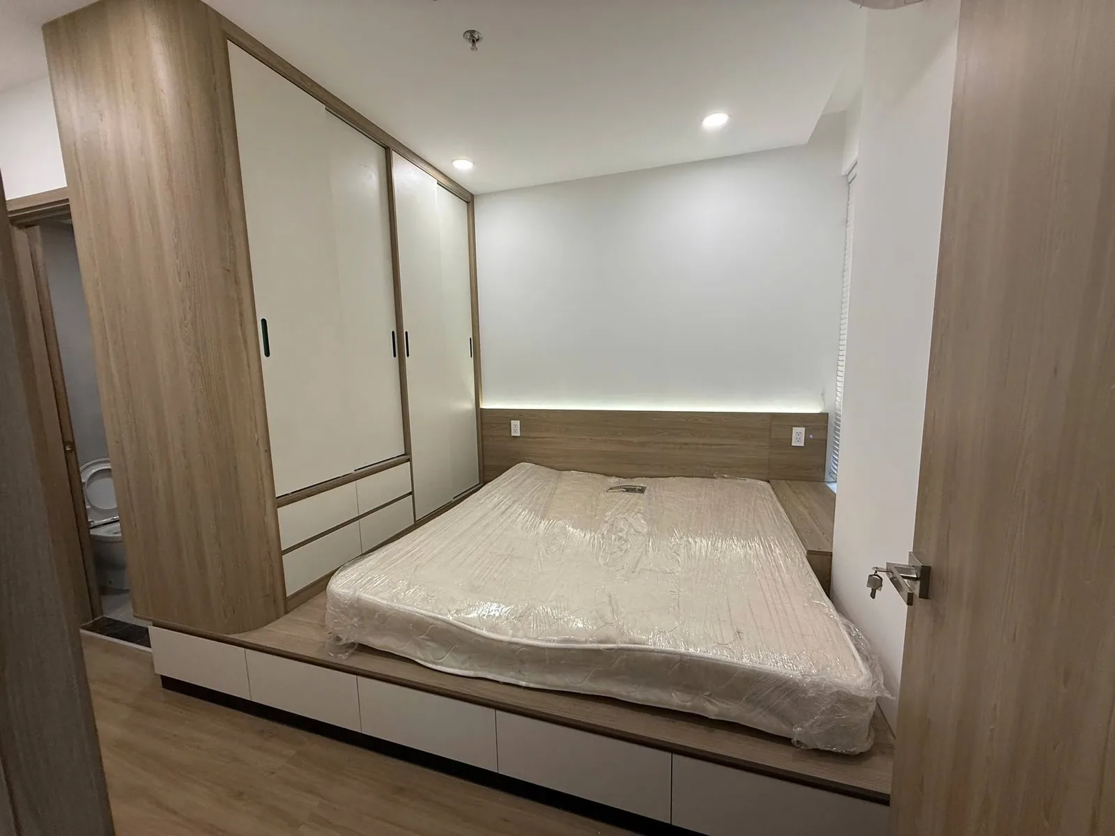 Tủ áo kịch trần và giường bục có LED Tủ quần áo kịch trần cánh trắng và giường bục gỗ có đèn LED hắt đầu giường – căn hộ Eastmark City