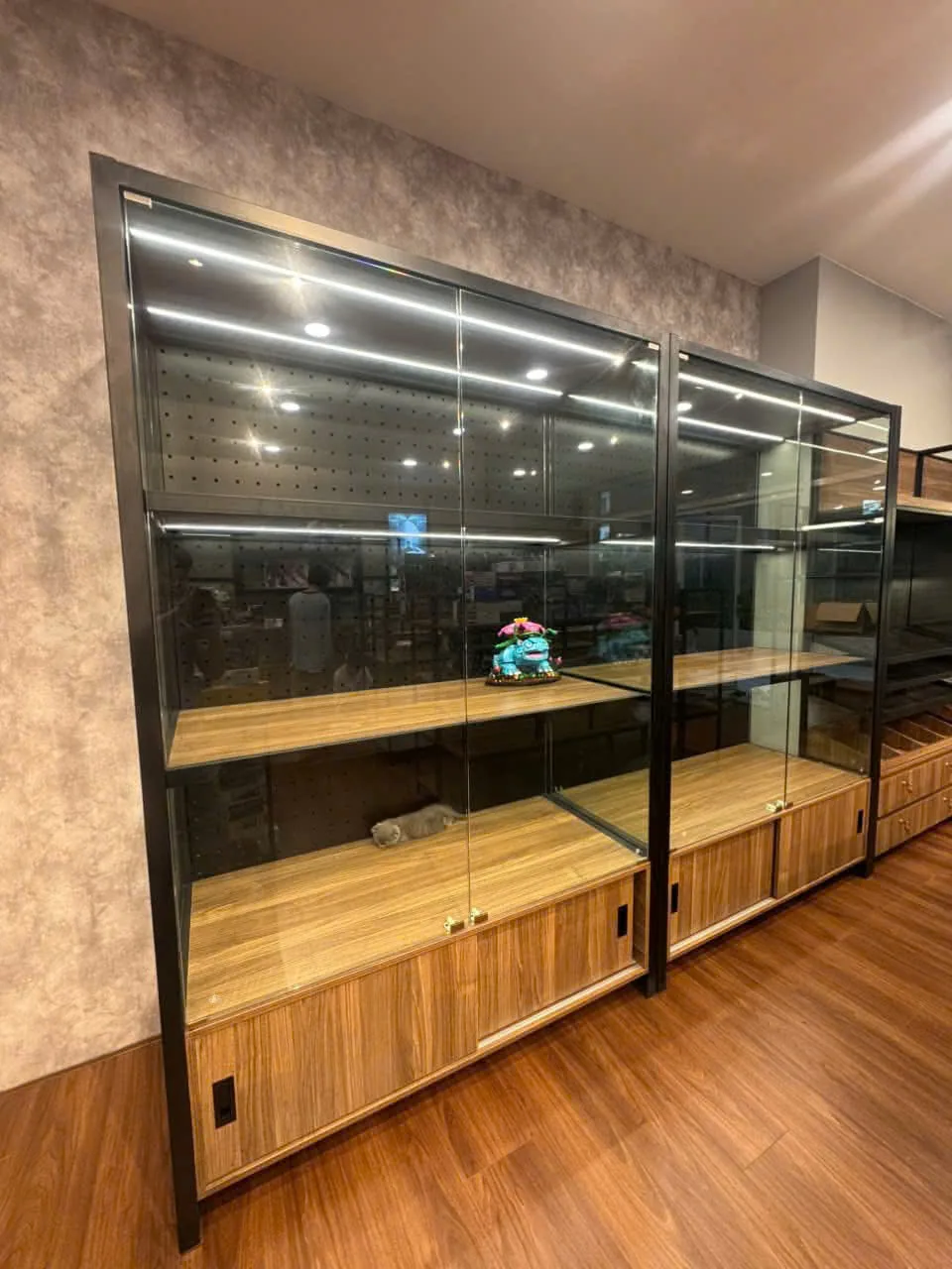 Tủ kính trưng bày khung đen, kệ gỗ và đèn LED cho shop mô hình